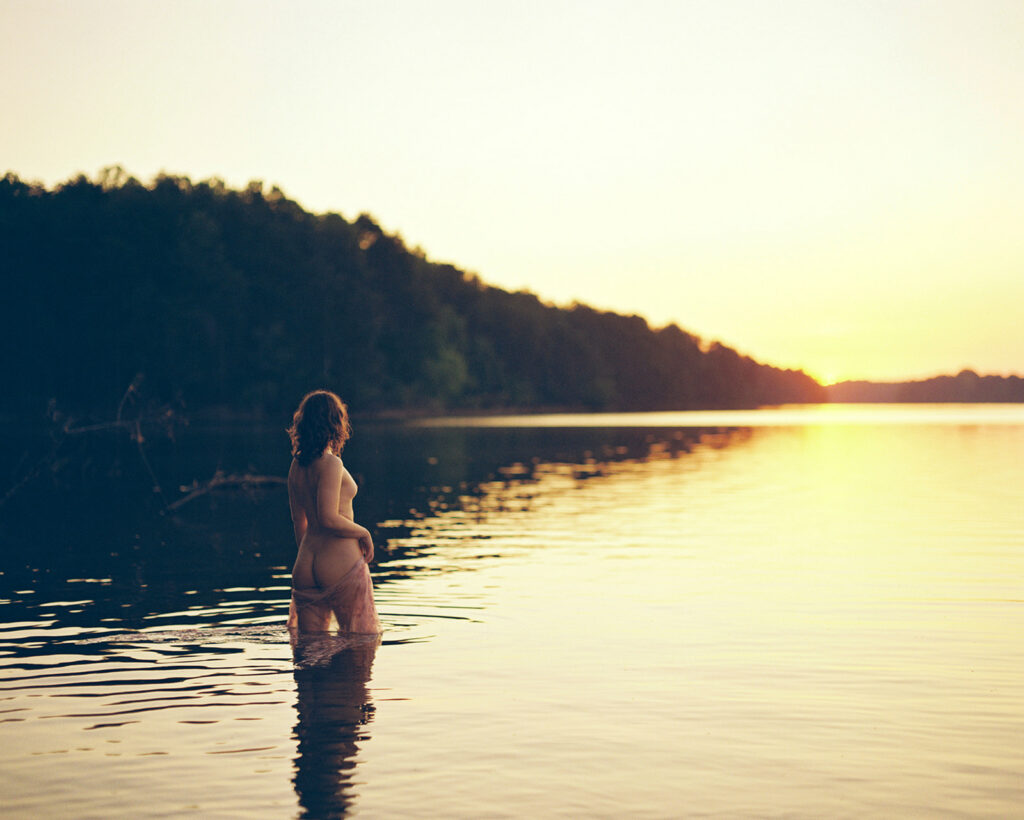 Nude woman silhouetted against sunrise on a still lake, fine art outdoor boudoir photography on film by K Hammock Photography Durham NC
