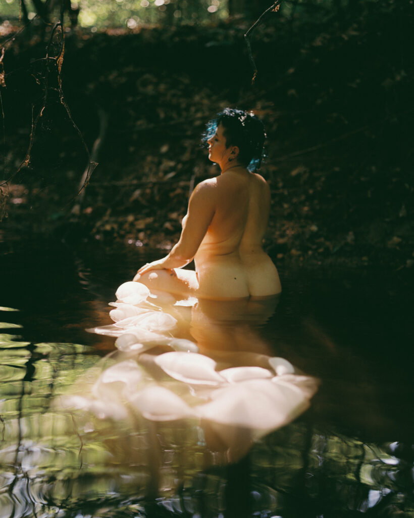 boudoir photograph in nature of a woman posing in sunlight in a creek, raleigh, nc