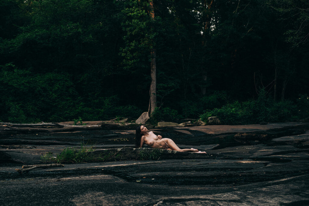 Woman laying on stone at a secluded outdoor boudoir location in cary, NC
