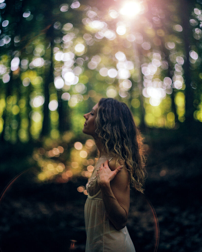 woman backlit by morning light through trees with curly hair, in durham, nc