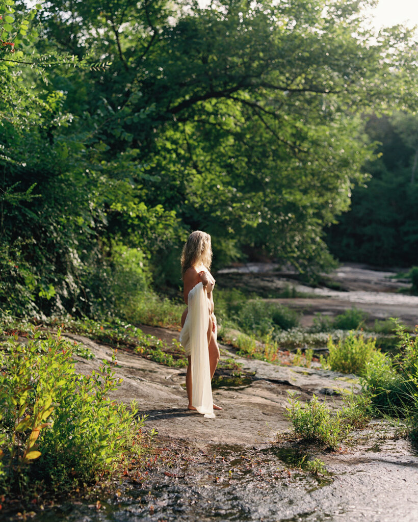 Woman in white fabric standing in golden morning light, fine art film boudoir photography by Kristen Hammock Durham NC