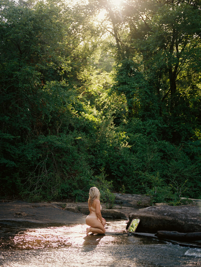 Nude woman admiring reflection in a mirror in golden morning light, fine art film boudoir photography by Kristen Hammock Durham NC