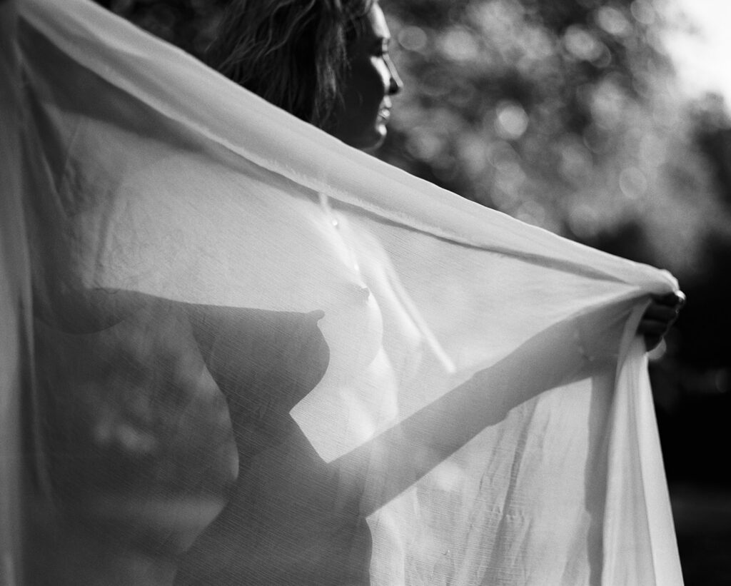 Woman wrapped in sheer fabric in black and white film at sunrise, outdoor fine art film photography by K Hammock Photography North Carolina