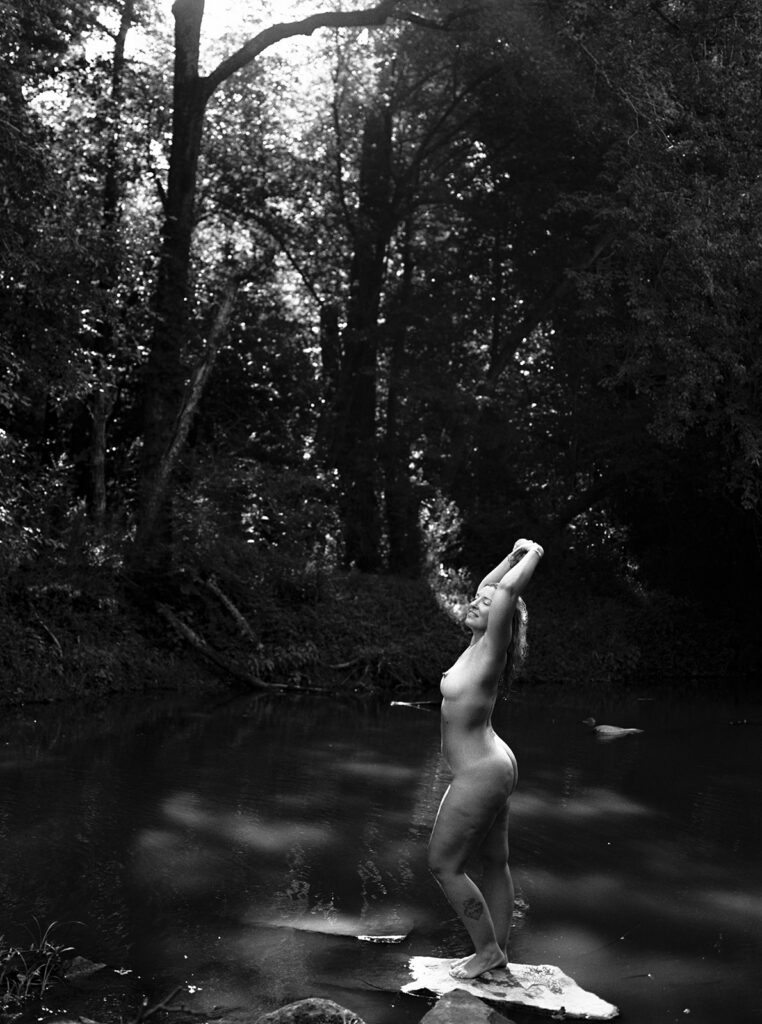 Woman raising hands standing in creek black and white photo, outdoor fine art film photography by K Hammock Photography North Carolina