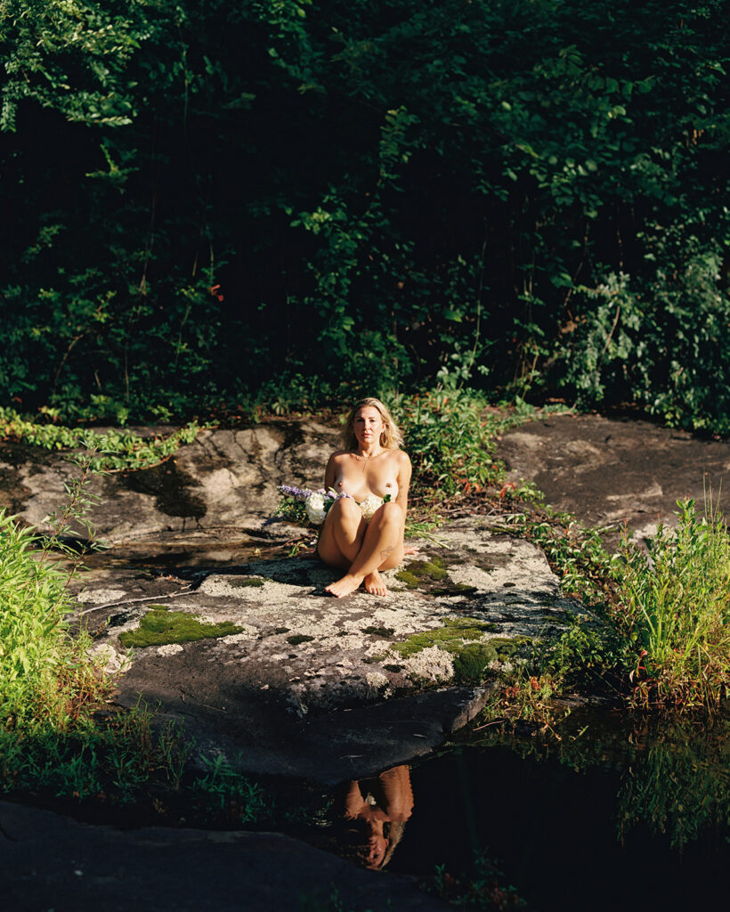 Woman wrapped in sunlight sitting on moss covered rock, outdoor fine art film photography by K Hammock Photography North Carolina