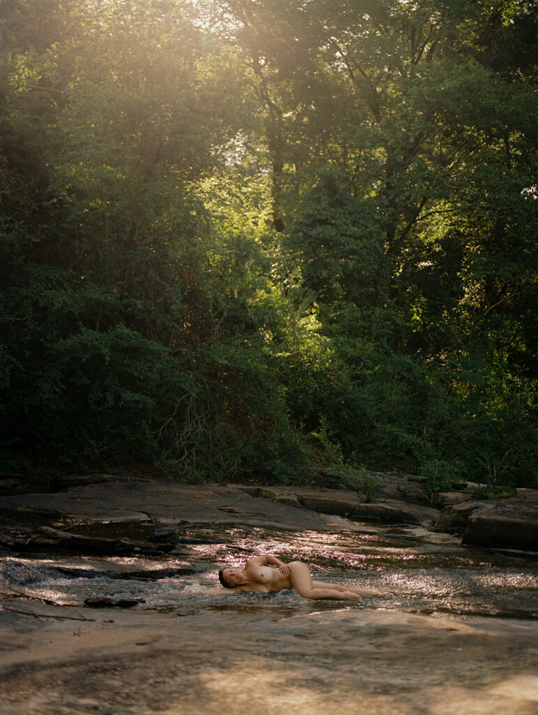 Nude woman laying in a creek in golden morning light, fine art film boudoir photography by Kristen Hammock Durham NC